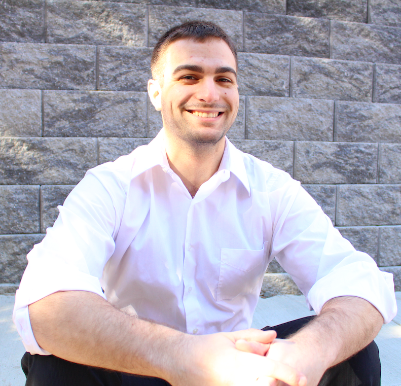 David smiling in front of gray brick