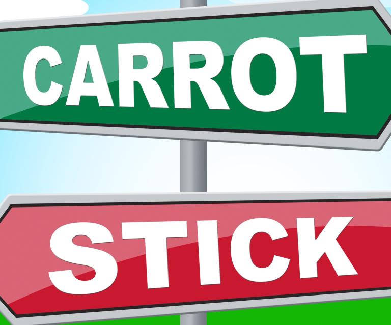 Two directional signs: one that reads "carrot" another that reads: "stick."