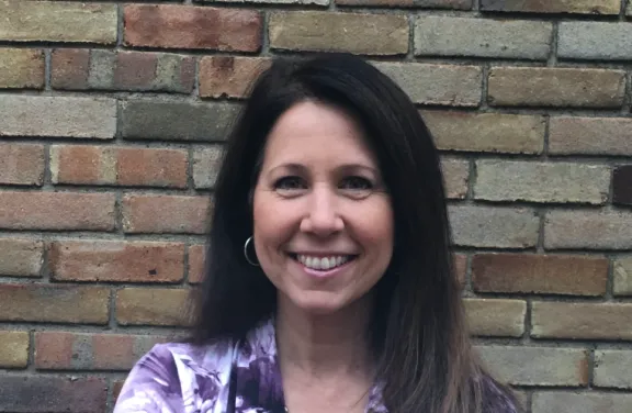 Lori smiling in front of a brick wall